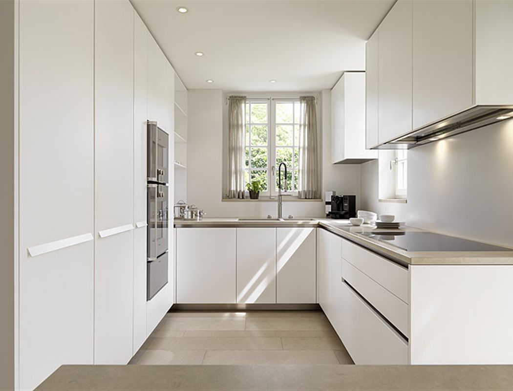 دکوراسیون آشپزخانه کوچک و مدرن که برای بزرگ تر جلوه دادن فضا، رنگ دیوارها و کابینت روشن و مشابه انتخاب شده است